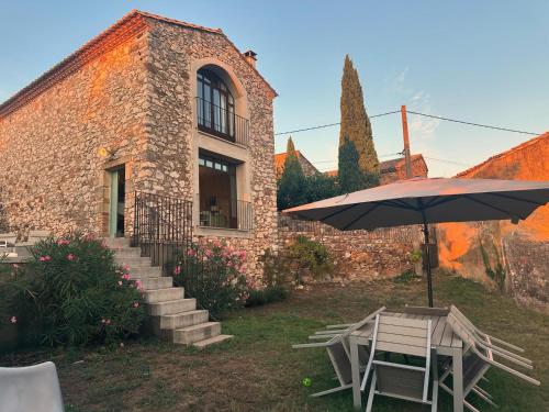 une table et un parasol devant un bâtiment dans l'établissement Mas Saint-Ferdinand - maison avec piscine, à La Capelle-et-Masmolène