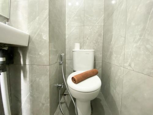 a bathroom with a toilet with a towel on it at Compact and Comfortable Studio Sayana Bekasi Apartment By Travelio in Bekasi