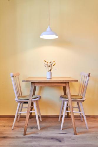 a wooden table with two chairs and a vase with flowers at Alte Seifensiederei - Astrid in Bad Tölz