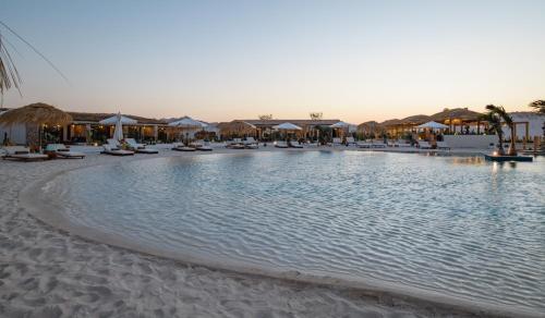 a large pool with chairs and umbrellas on a beach at Marmarica Boutique Cabanas - Ras El Hekma - North Coast Top Rated Luxury Stay in Marsa Matruh