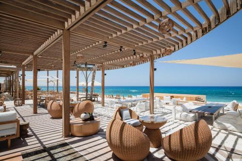 an outdoor patio with chairs and tables and the ocean at Marmarica Boutique Cabanas - Ras El Hekma - North Coast Top Rated Luxury Stay in Marsa Matruh