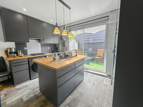 une cuisine avec des armoires grises et une grande fenêtre dans l'établissement La Maison des Saisons - Paris - La Défense ARENA, à Carrières-sur-Seine