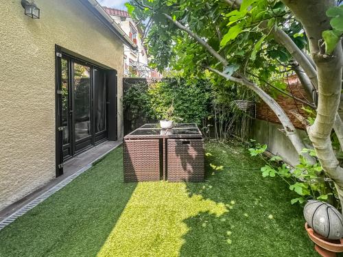 un jardin avec une cage pour oiseaux sur l'herbe dans l'établissement La Maison des Saisons - Paris - La Défense ARENA, à Carrières-sur-Seine