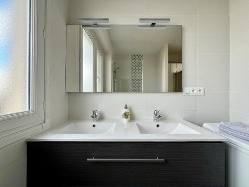 une salle de bain avec deux lavabos et un grand miroir dans l'établissement Grand Appartement à Deux Pas De La Vieille Ville, à Vannes