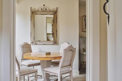 a dining room with a table and chairs and a mirror at Lovedays Cottage, A Luxury 16th Century home in Painswick in Painswick
