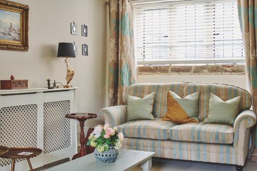 a living room with a couch and a window at Lovedays Cottage, A Luxury 16th Century home in Painswick in Painswick