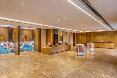 a banquet hall with white tables and white chairs at The Leela Ambience Convention Hotel Delhi in New Delhi