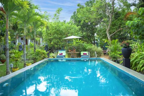 a swimming pool in a resort with palm trees at Arcadia Resort in Hikkaduwa