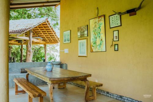 a wooden table and benches next to a wall at Rivendell Twisted Tree in Kurunegala