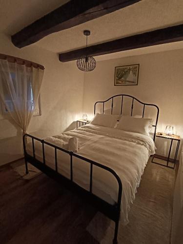 a bedroom with a large bed with white sheets and a chandelier at Galoma Korana in Gornji Velemerić