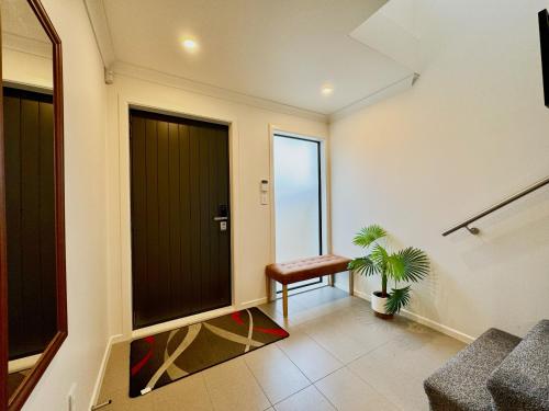 a hallway with a black door and a plant at NO PARTY ALLOWED, Entire Brand New 3 bedroom townhouse, free unlimited fibre wifi and free parking in Wellington