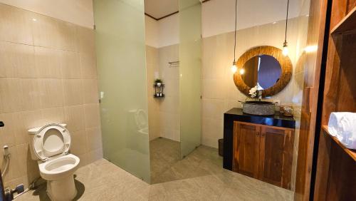 a bathroom with a toilet and a mirror at Weda Villas in Ubud