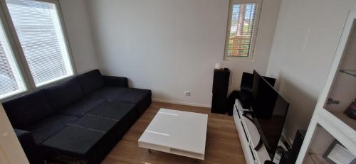 a living room with a black couch and a tv at Villa Koivunoksa in Kerava
