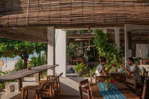 two people sitting at a table in a restaurant at Mr Kahawa in Paje