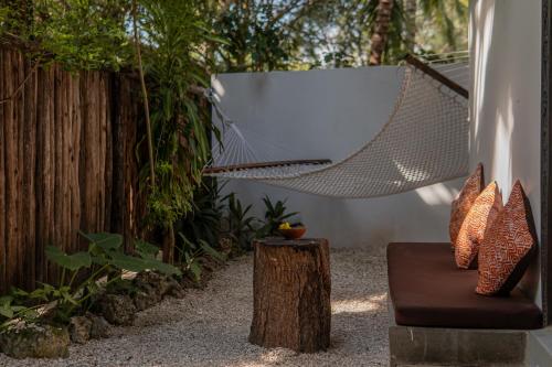 a hammock in a garden with a tree stump at Mr Kahawa in Paje