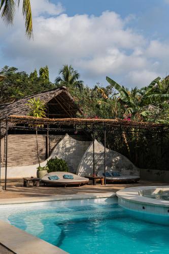 a swimming pool next to a resort with a surfboard at Mr Kahawa in Paje