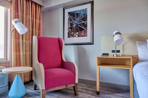 a bedroom with a pink chair and a bed at Hilton Garden Inn Anchorage in Anchorage