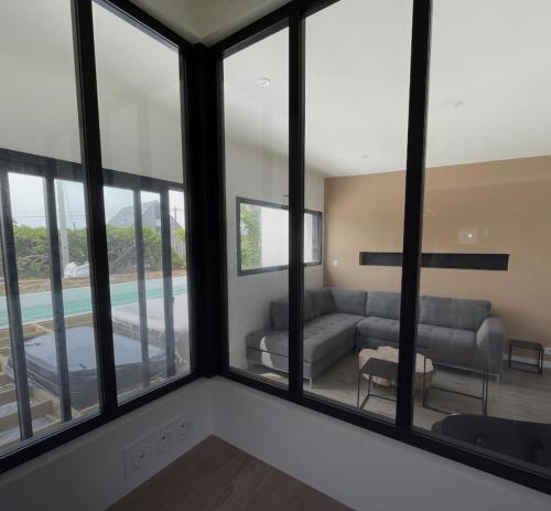 - un salon avec de grandes fenêtres et un canapé dans l'établissement Villa Soizic, à La Terre du Pont