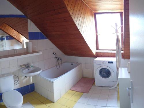 a bathroom with a tub sink and a washing machine at Apartmán Zukalka 2kk in Vítkovice
