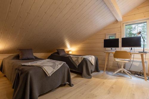 a room with two beds and a desk with two monitors at Villa Sylvi by Hi Ylläs in Äkäslompolo