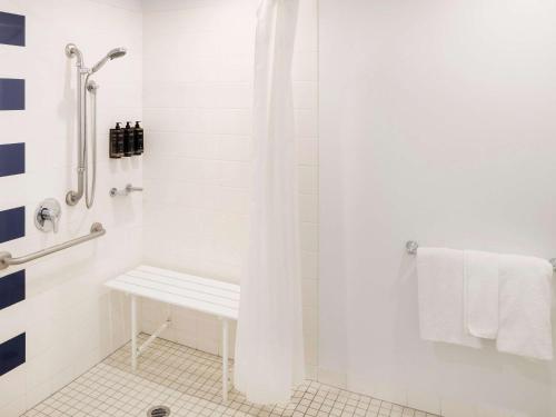 悉尼Mercure Sydney Macquarie Park的白色的浴室设有淋浴和长凳