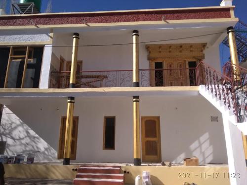 a large white house with yellow columns at Kunsal Yourdum Homestay Ladakh by LexStays in Leh
