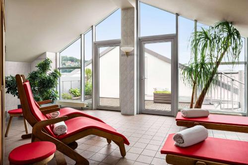 a living room with large windows and red furniture at Vienna House by Wyndham Thüringer Hof Eisenach in Eisenach