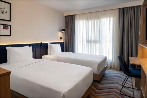 a hotel room with two beds and a desk at Hampton By Hilton Istanbul Merter in Istanbul