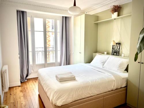 une chambre avec un grand lit blanc et une fenêtre dans l'établissement Jerickais Appartement 3 pièces à Pantin, à Pantin