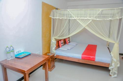 a bedroom with a canopy bed and a wooden table at A One Calm Palace in Mirissa