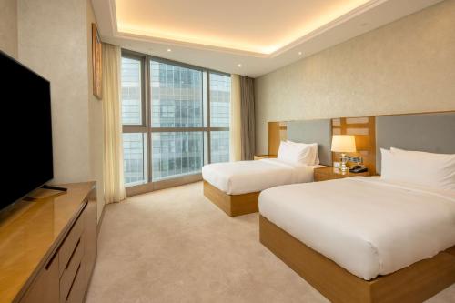 a hotel room with two beds and a flat screen tv at Hilton Brazzaville Les Tours Jumelles Hotel & Residences in Brazzaville