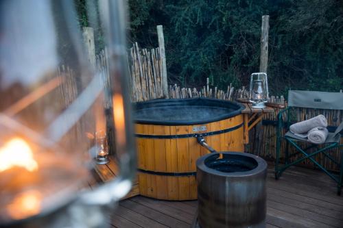 a wooden tub sitting on a deck with a table at Quatermain's 1920's Safari Camp – Amakhala Game Reserve in Amakhala Game Reserve