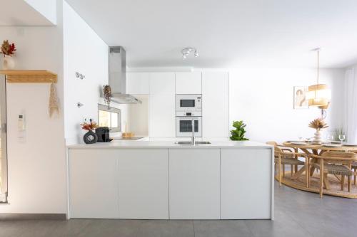 a white kitchen with a sink and a table at Stylish 3-Bedroom Villa Haven with a Private Pool in Albufeira