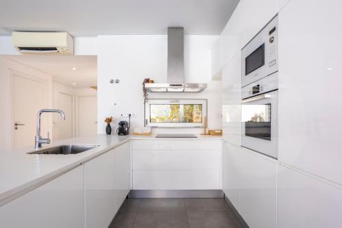 a white kitchen with white cabinets and a sink at Stylish 3-Bedroom Villa Haven with a Private Pool in Albufeira
