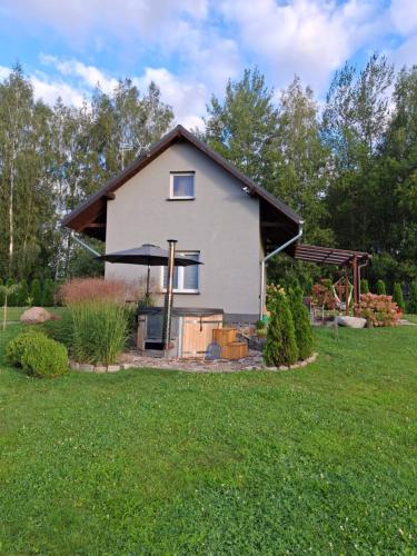 a white house with a black roof in a yard at Zacisze pod brzozami in Kętrzyn