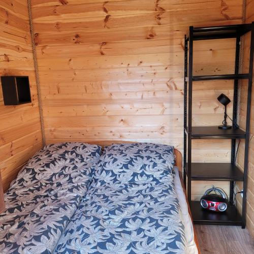 a bed in a room with a wooden wall at Domek dla dwojga in Pelnik