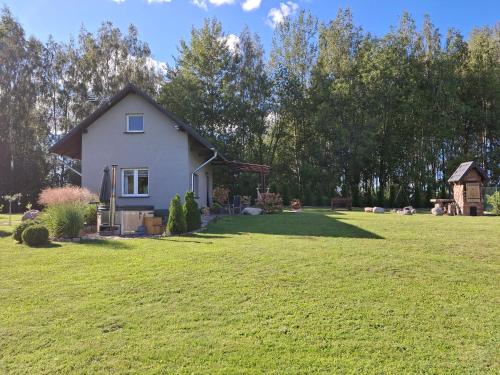 a small white house in a field of grass at Zacisze pod brzozami in Kętrzyn