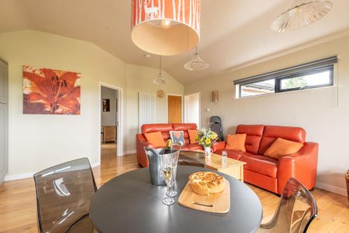 a living room with a table and a couch at Tor Farm Lodges - Private Hot Tubs, Shared Seasonal Outdoor Pool, Dog Friendly in Cheddar
