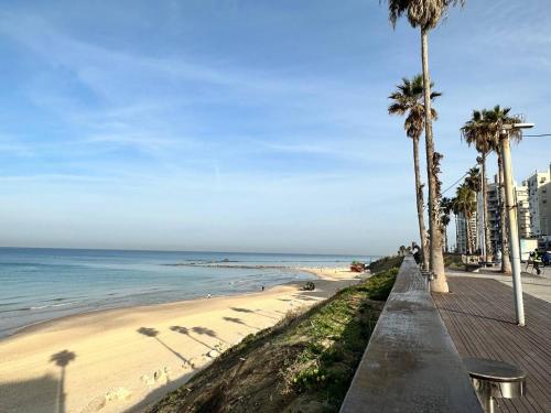 a sandy beach with palm trees and the ocean at Pardisano in Bat Yam