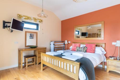 a bedroom with a bed with orange walls at Tor Farm Lodges - Private Hot Tubs, Shared Seasonal Outdoor Pool, Dog Friendly in Cheddar