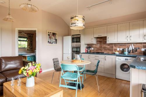 a kitchen with a table and chairs in a room at Tor Farm Lodges - Private Hot Tubs, Shared Seasonal Outdoor Pool, Dog Friendly in Cheddar