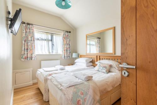 a bedroom with two beds and a mirror at Tor Farm Lodges - Private Hot Tubs, Shared Seasonal Outdoor Pool, Dog Friendly in Cheddar
