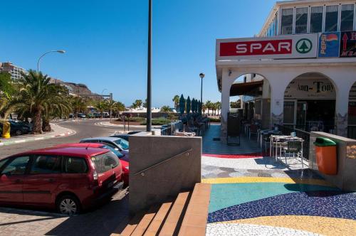 a red car parked in front of a store at Beachfront Apartment Playa del Cura 3 by VillaGranCanaria in Playa del Cura