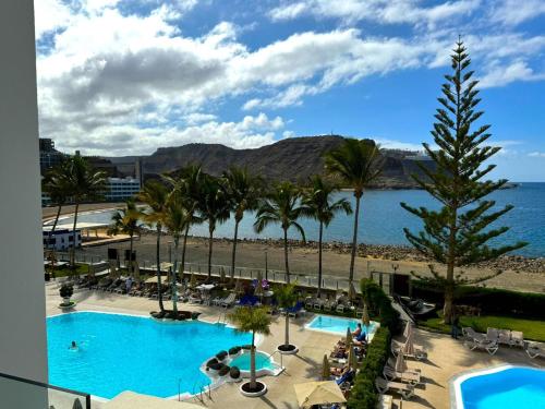 a resort with a pool and palm trees and the ocean at Beachfront Apartment Playa del Cura 3 by VillaGranCanaria in Playa del Cura