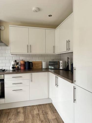 a white kitchen with white cabinets and wooden floors at Practical 2 Bedroom House Perfect for Contractors in Grimsby by PureStay - 7 night min! in Grimsby