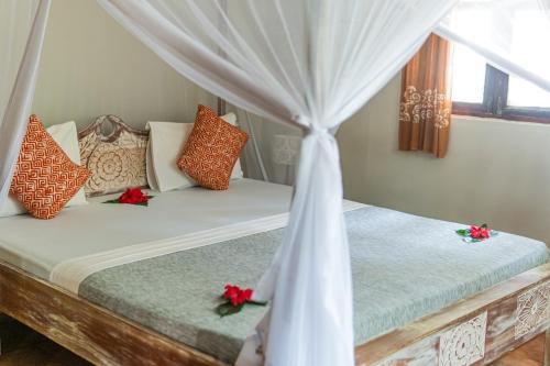 two beds in a bedroom with red flowers on them at Mr Kahawa in Paje
