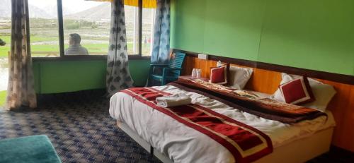 a bed in a room with a woman looking out the window at Full Moon Cottages Pangong Ladakh by LexStays in Kakstet