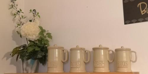 a row of silver mugs on a shelf with a vase at L'Empire D'Essences Appartement in Valréas