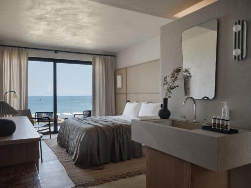 a hotel room with a bed and a sink at Port Royal Villas and Spa - Adults Only in Kolimbia