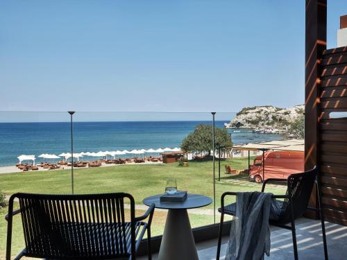 a patio with a table and chairs and the ocean at Port Royal Villas and Spa - Adults Only in Kolimbia